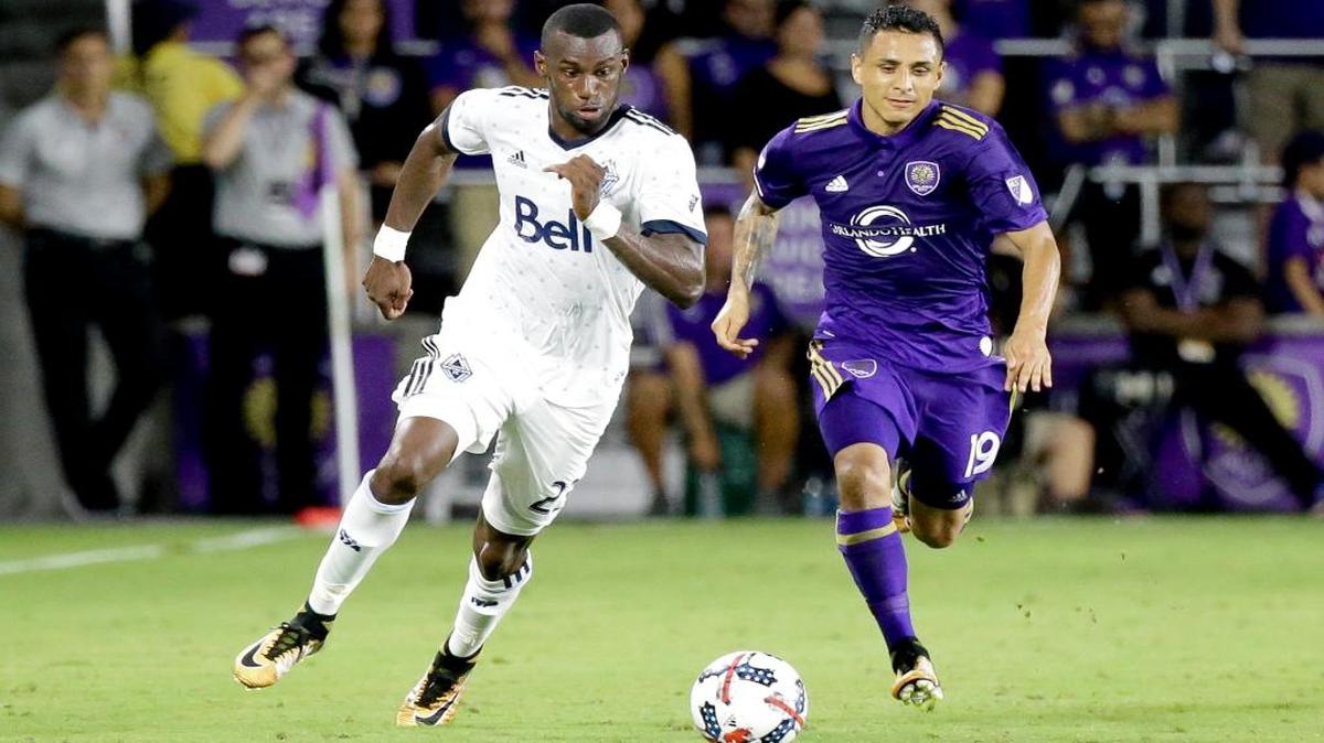 Bernie Ibini (izq.), de los Whitecaps de Vancouver, escapa seguido por Yoshimar Yotún (19), del Orlando City, el 26 de agosto del 2017, en Orlando, Florida.