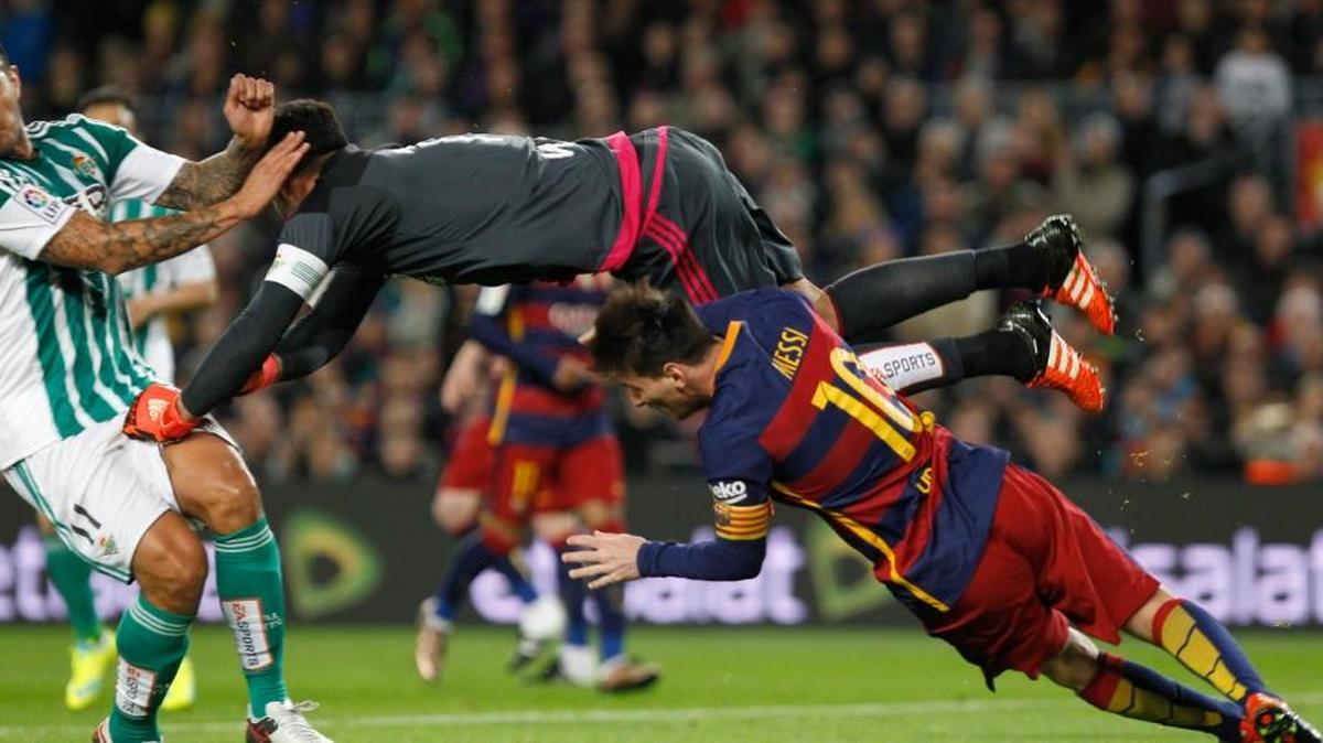 El portero del Real Betis Adán (izq.) despeja un balón ante la llegada del delantero argentino del FC Barcelona Leo Messi en la jugada que ha supuesto penalti a favor del equipo azulgrana.