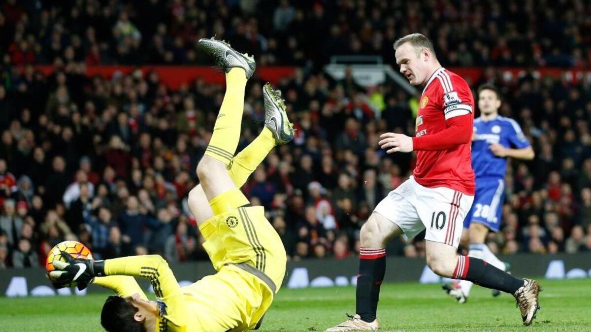 El arquero del Chelsea Thibaut Courtois atrapa una bola con dificultad ante la amenaza del ariete del Manchester United Wayne Rooney, por la Premier League, en el Old Trafford Stadium, en Manchester, Inglaterra, el lunes.