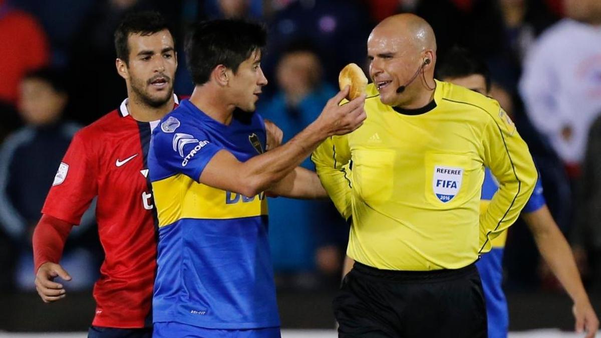 Pablo Perez, de Boca Juniors de Argentina, muestra al árbitro Francisco Chacón, de México, un objeto que le arrojaron en el choque por la Copa Libertadores, contra el paraguayo Cerro Porteño, en Asunción, el jueves 28 de abril del 2016.