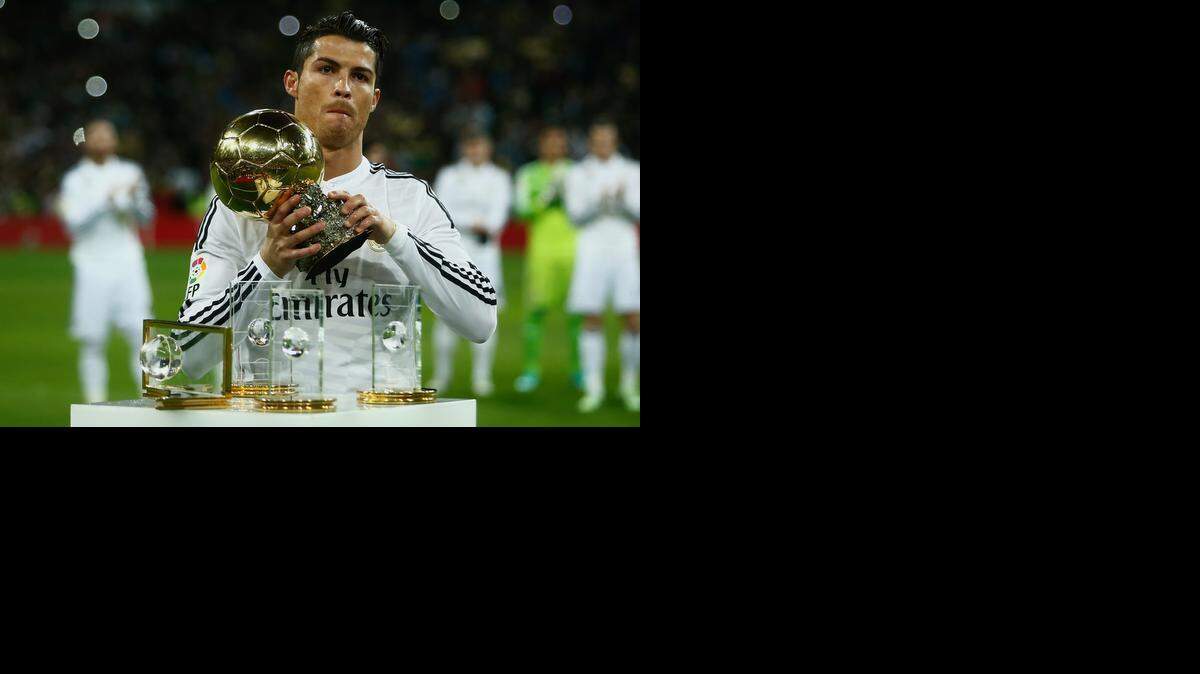 
El delantero del Real Madrid, Cristiano Ronaldo, levanta el Balón de Oro ante las miradas de los aficionados merengues en el Santiago Bernabéu, el 15 de enero de 2015.
