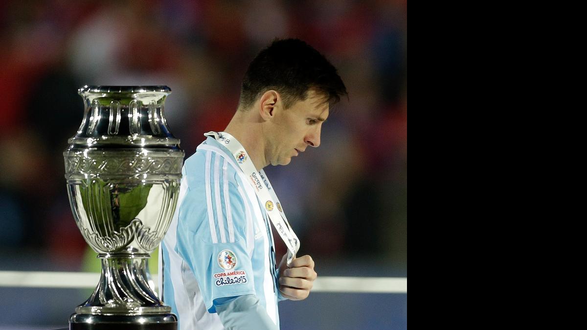 
 Lionel Messi, con su medalla de plata, pasa por el lado del trofeo de la Copa América 2015.

