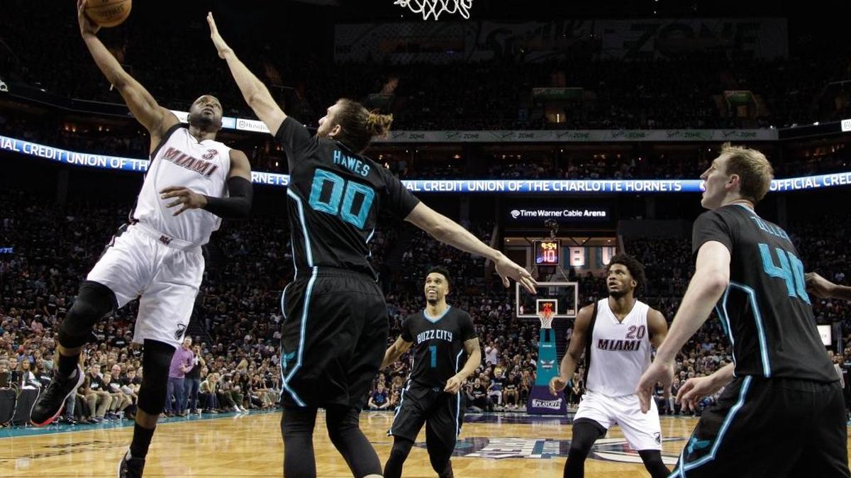 En plena acción, Dwyane Wade, del Heat, se dispone a tirar marcado por Spencer Hawes, de los Hornets, el sábado 23 de abril del 2016, en Charlotte, Carolina del Norte. Los Hornets ganaron 96-80.