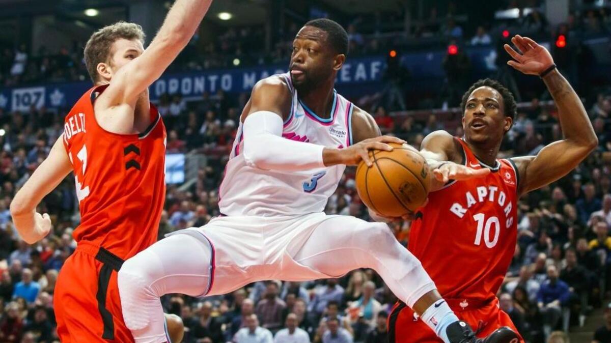 Dwyane Wade, del Heat, pasa el balón pasa el balón entre los jugadores de los Raptors Jakob Poeltl (izq.) y DeMar DeRozan el 13 de febrero en Toronto.