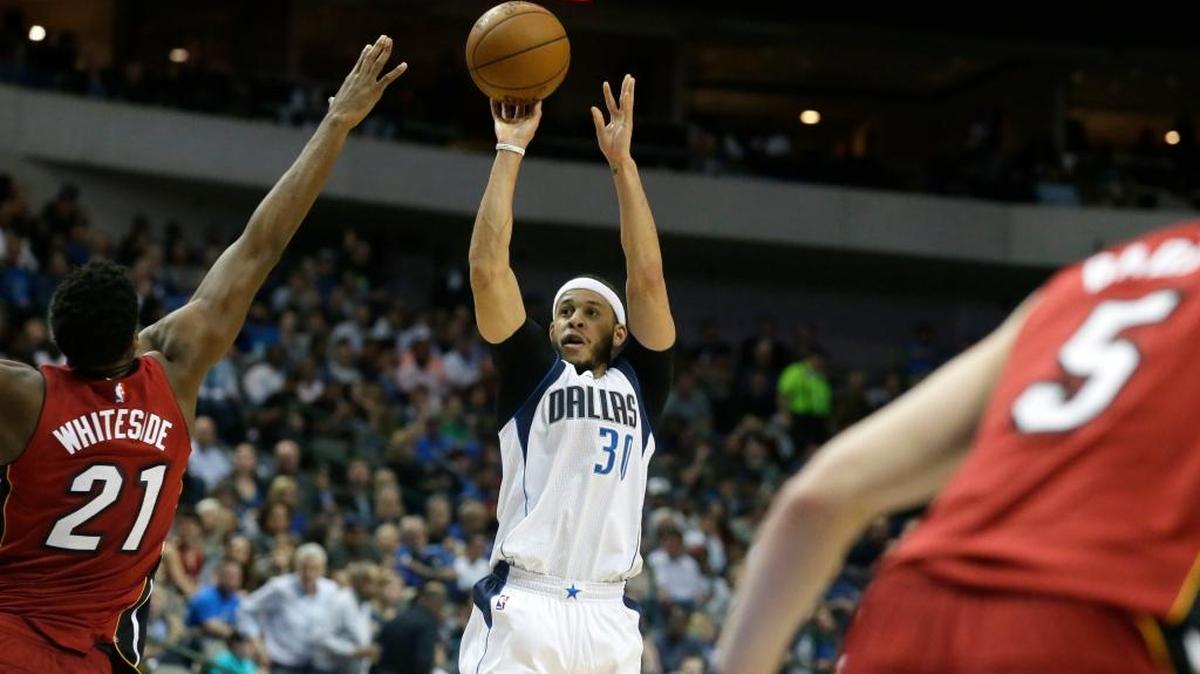 Seth Curry (30), de los Mavericks, dispara sobre la marcación de Hassan Whiteside (21), del Heat, en Dallas, la noche del lunes 27 de febrero del 2017.