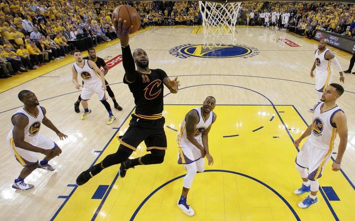 El astro de los Cavaliers LeBron James (23) penetra al aro entre os jugadores de los Warriors.