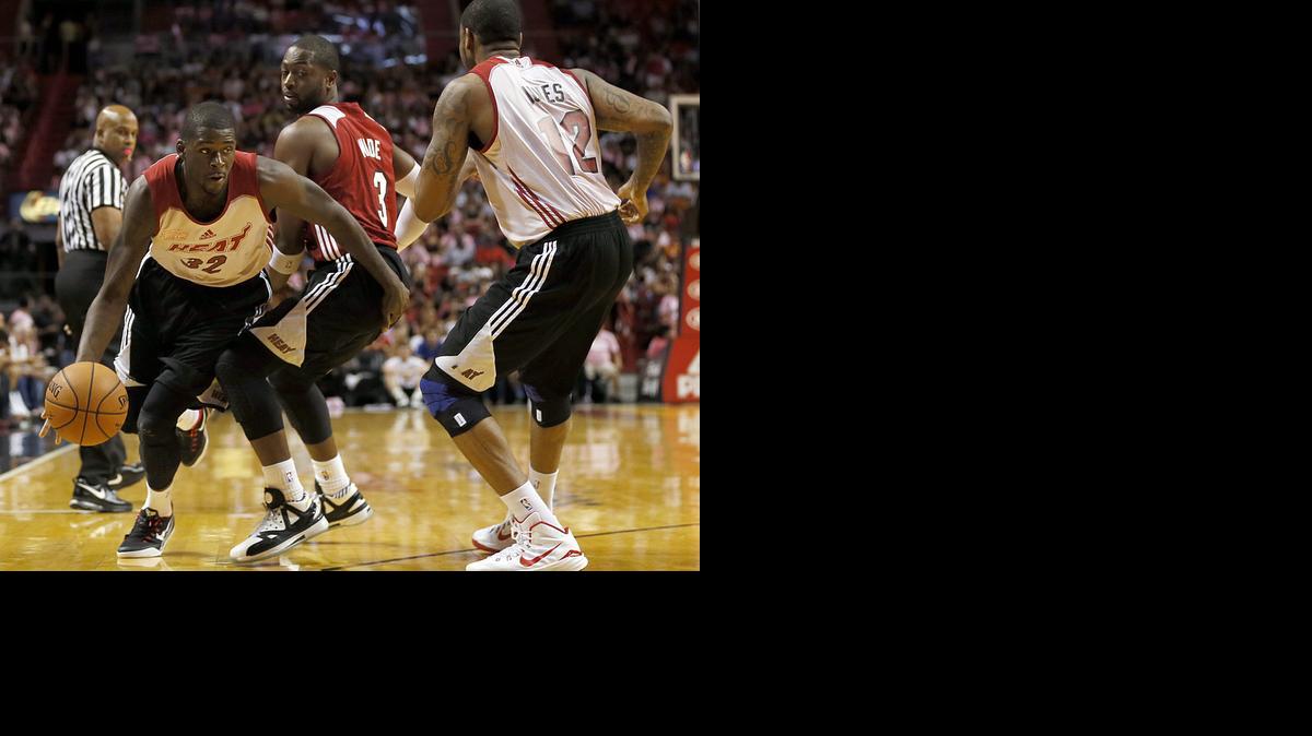 
James Ennis (izq.) elude la marca de Dwyane Wade (centro) en un juego de práctica entre los equipos Blanco y Rojo del Heat, el miércoles en Miami.


