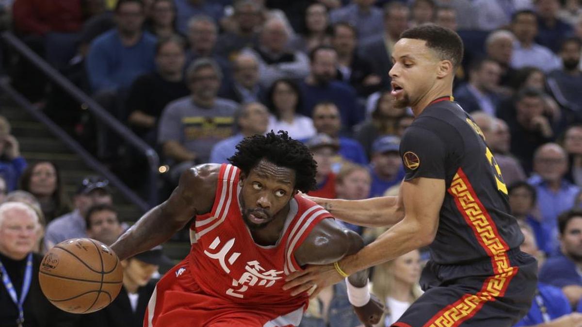 El armador de Houston Patrick Beverley (izq.) trata de burlar la marca de Stephen Curry, de los Warriors, en el partido celebrado el 9 de febrero del 2016.