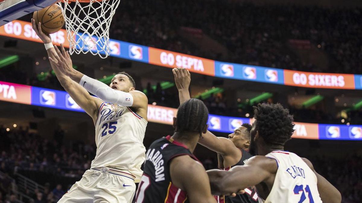 El jugador de los 76ers Ben Simmons (der.) anota una bandeja ante los jugadores del Heat Josh Richardson (0) y Hassan Whiteside este viernes en filadelfia.