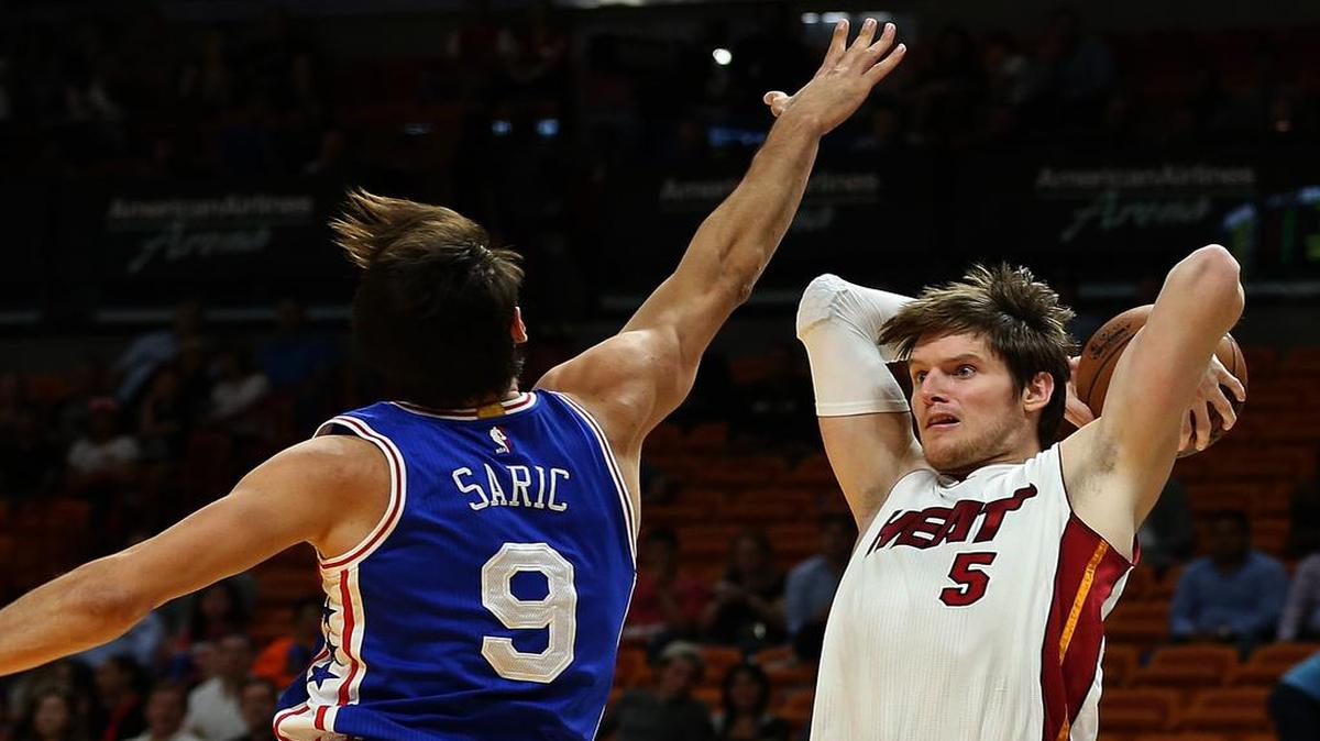 Luke Babbitt, del Heat, busca pasar la bola sobre Dario Saric, de los 76ers, en el AmericanAirlines Arena en Miami, el 12 de octubre del 2016.