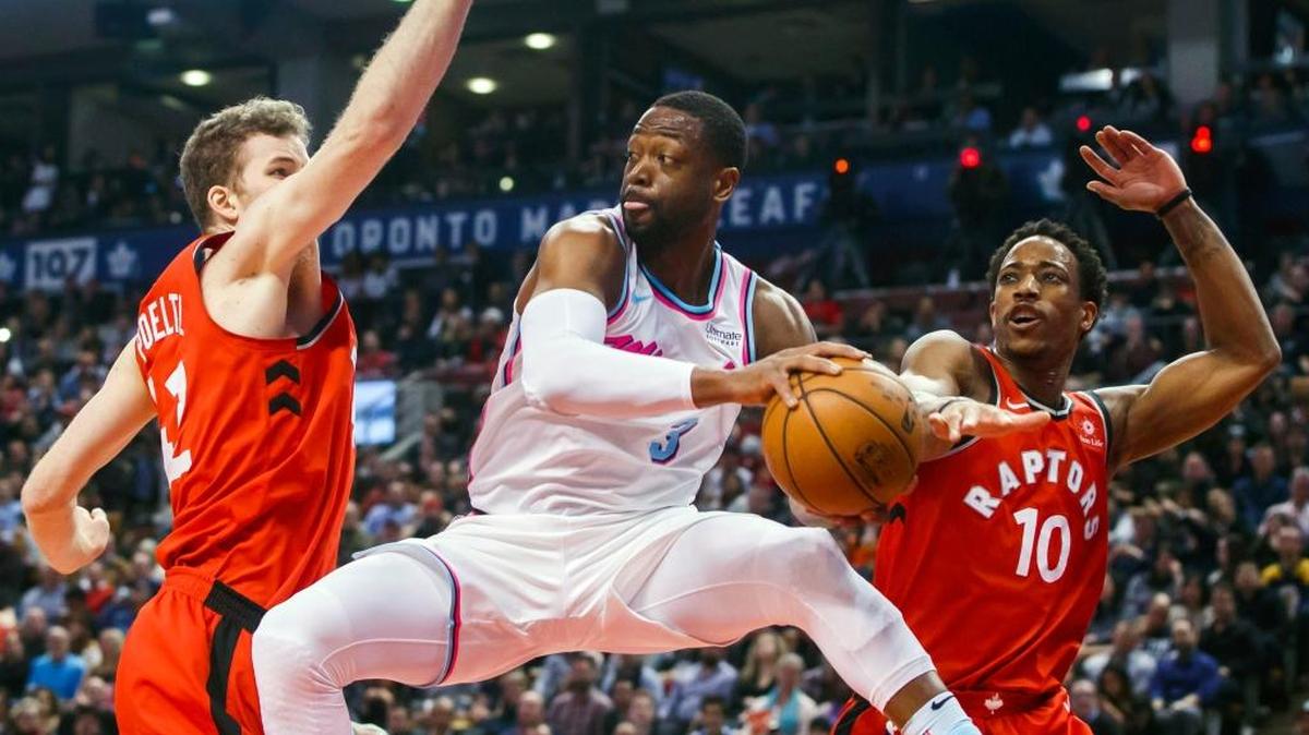 Dwyane Wade, del Heat, pasa el balón entre los jugadores de los Raptors Jakob Poeltl y DeMar DeRozan (der.) el martes en Toronto.