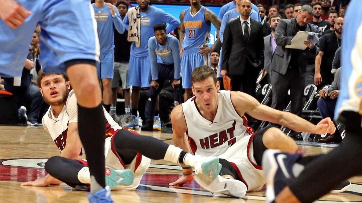 Los jugadores del Heat Tyler Johnson (izq.) y Goran Dragic caen sobre la cancha en los segundos finales en la derrota ante los Nuggets el domingo en el American Airlines Arena.