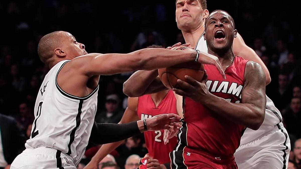El escolta del Heat Dion Waiters trata de entrar al aro entre los jugadores de los Nets Randy Foye (izq.) y Brook Lopez (der.), este miércoles en Nueva York.
