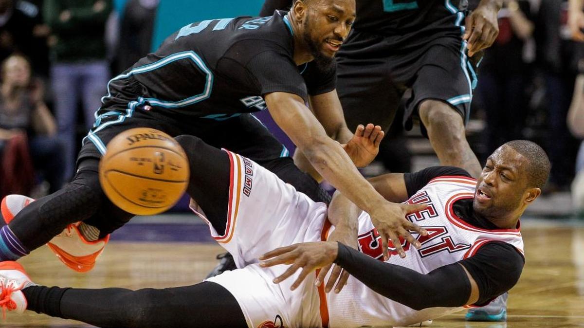 Desde el piso, Dwyane Wade pasa la bola sobre Kemba Walker, de los Hornets, la noche del viernes 5 de febrero del 2016, en Charlotte, Carolina del Norte. Miami ganó 98-95.