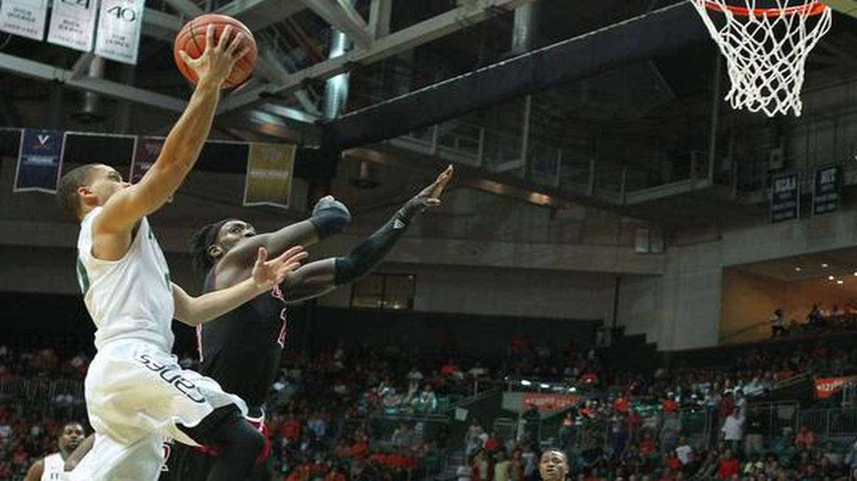 El jugador de los Huracanes Manu Lecomte (izq.) trata de anotar una canasta ante la defensa de Montrezl Harrell, de los Cardinals de Louisville, el martes en el BankUnited Center en Coral Gables.
