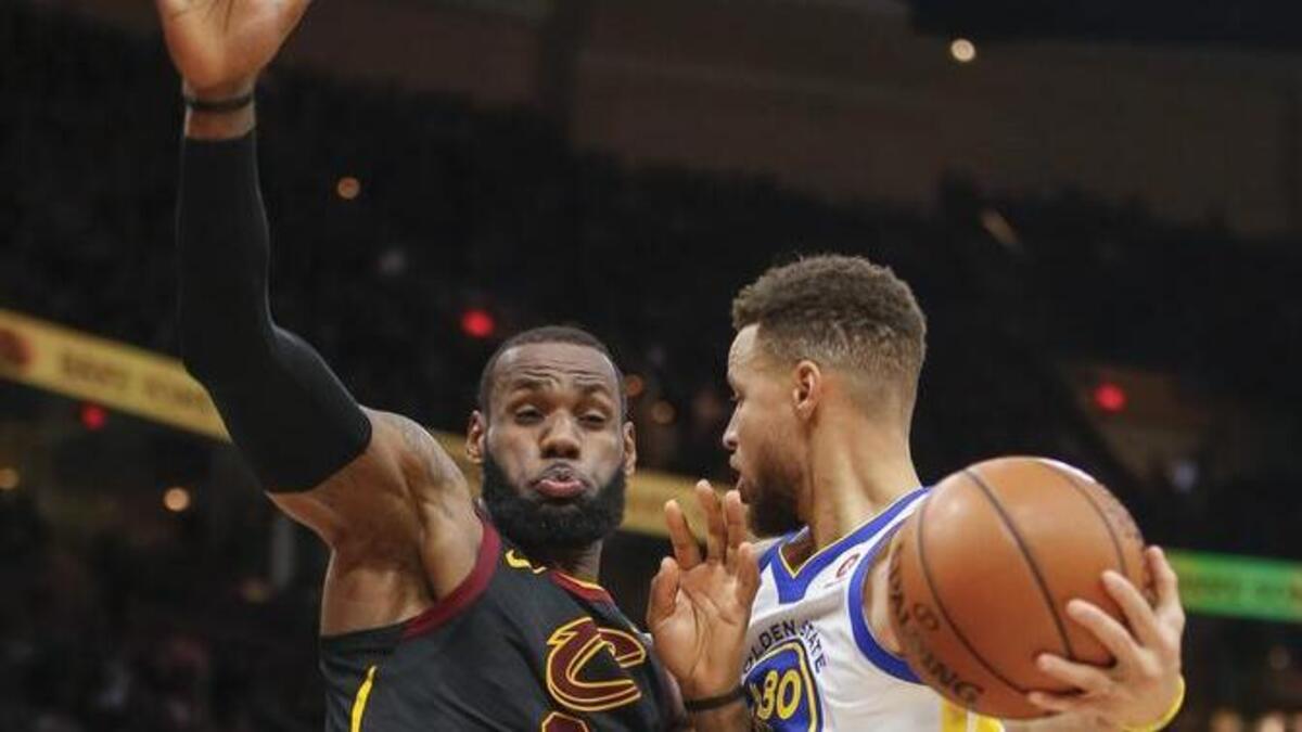 LeBron James, de los Cavs (izq.), trata de impedir la jugada de Stephen Curry, de los Warriors, el 15 de enero en Cleveland.
