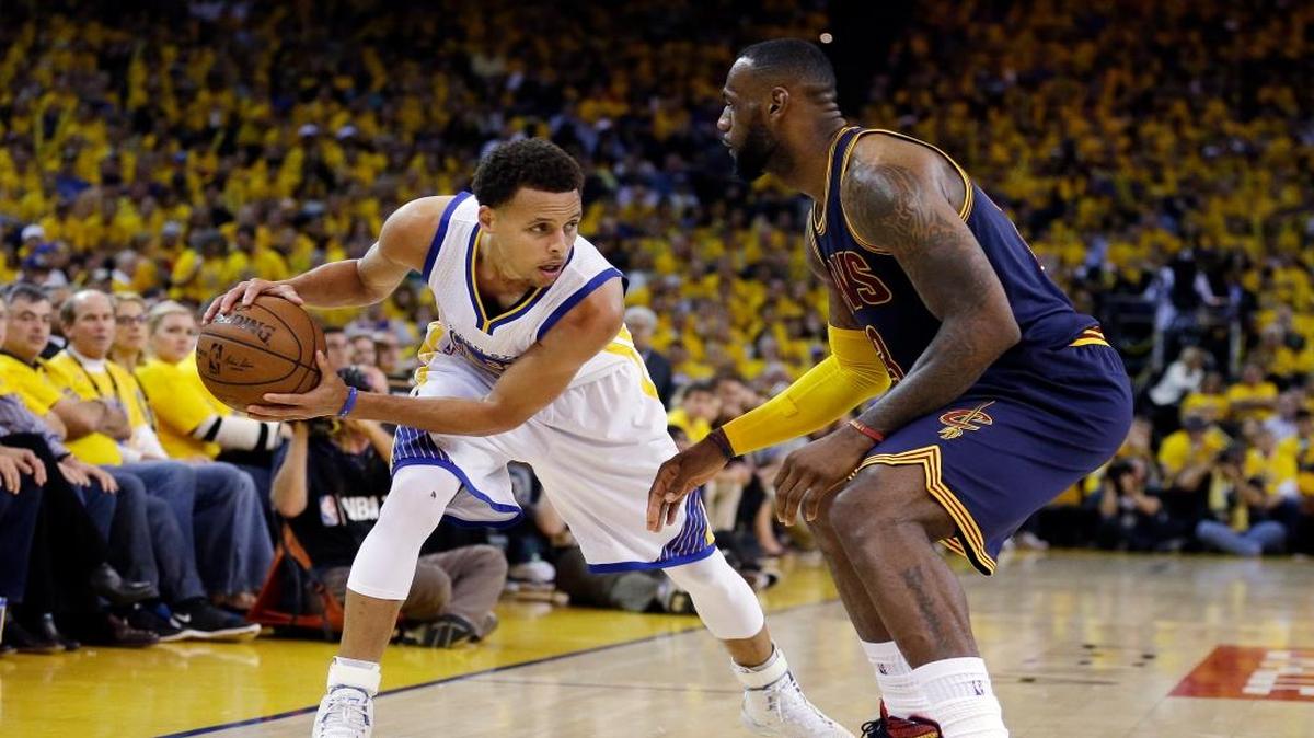 Stephen Curry, de los Warriors, trata de burlar la marca de LeBron James, de los Cavs (der.), en las Finales del 2015.
