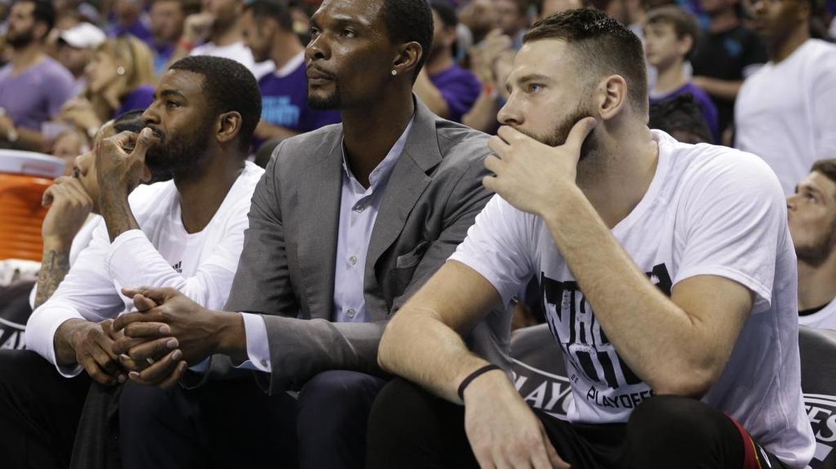 Chris Bosh (centro) observa junto a Josh McRoberts un juego del Heat contra los Hornets el 29 de abril del 2016.
