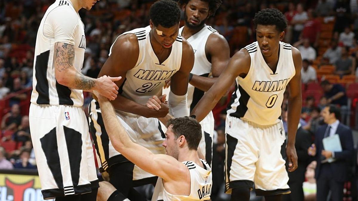 Los jugadores del Heat Tyler Johnson, Hassan Whiteside, Justise Winslow y Josh Richardson (de der. a izq.) ayudan a levantar a Goran Dragic en el juego ante el Magic, el martes en el American Airlines Arena.
