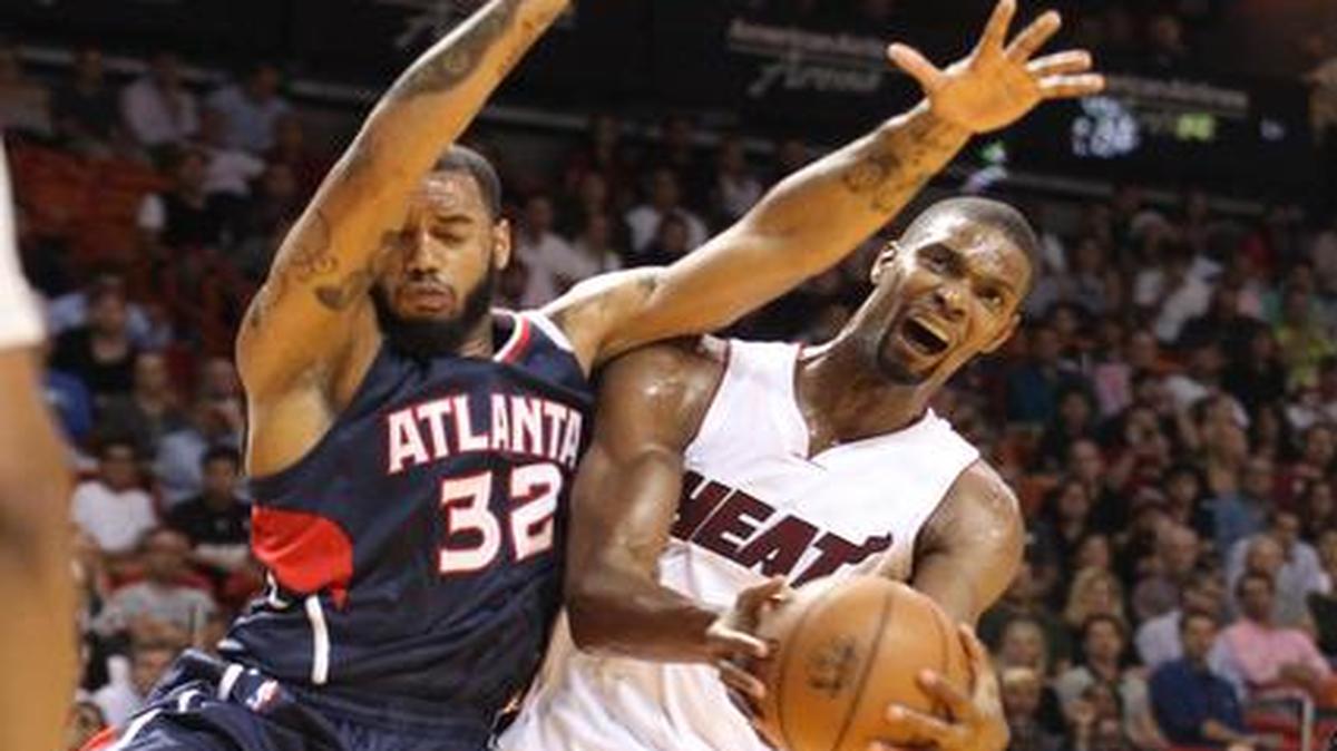 
Chris Bosh, del Heat, sufre una falta de Mike Scott, de los Hawks, el miércoles en la AAA en Miami.

