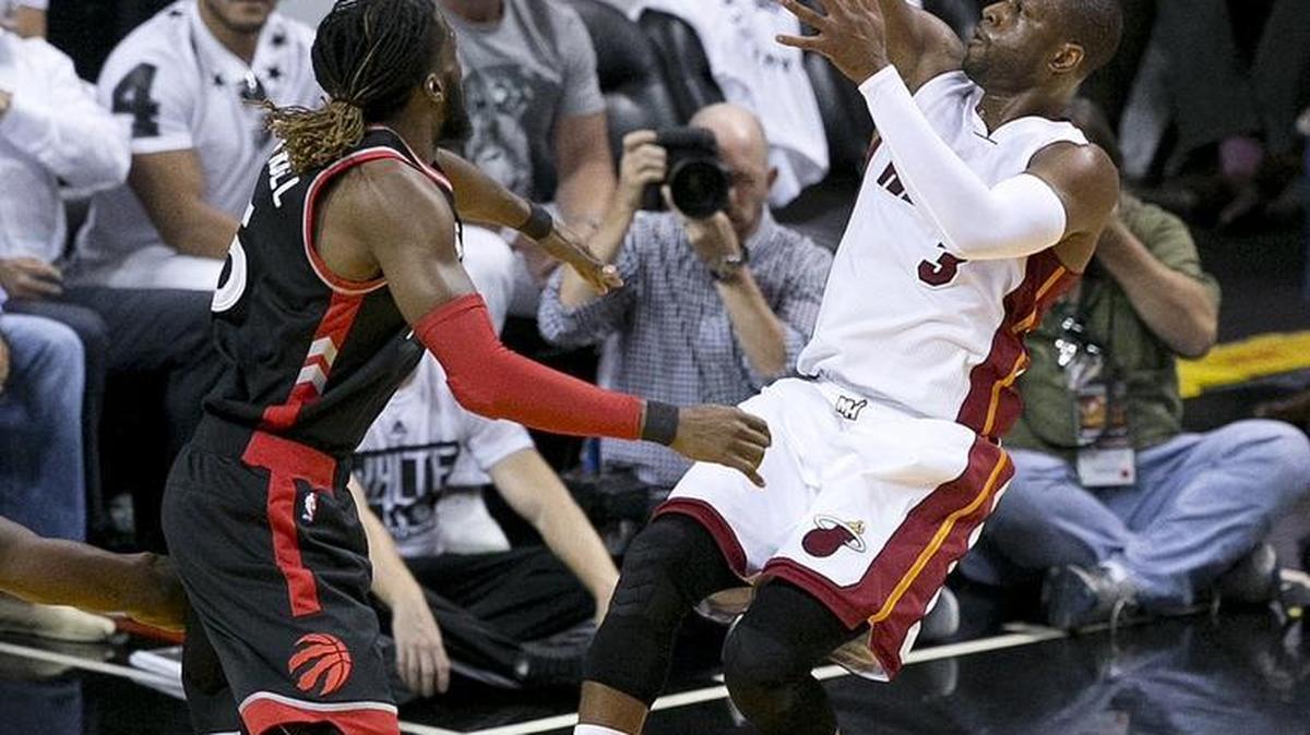 El escolta del Heat Dwyane Wade anota ante el delantero de los Raptors DeMarre Carroll (izq.) el lunes en el American Airlines Arena.