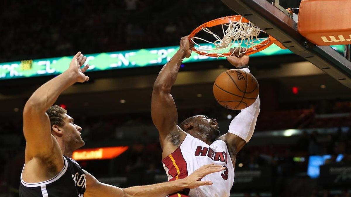 Dwyane Wade (der.) clava la pelota ante la marca de Brook López, de los Nets, el lunes en Miami.
