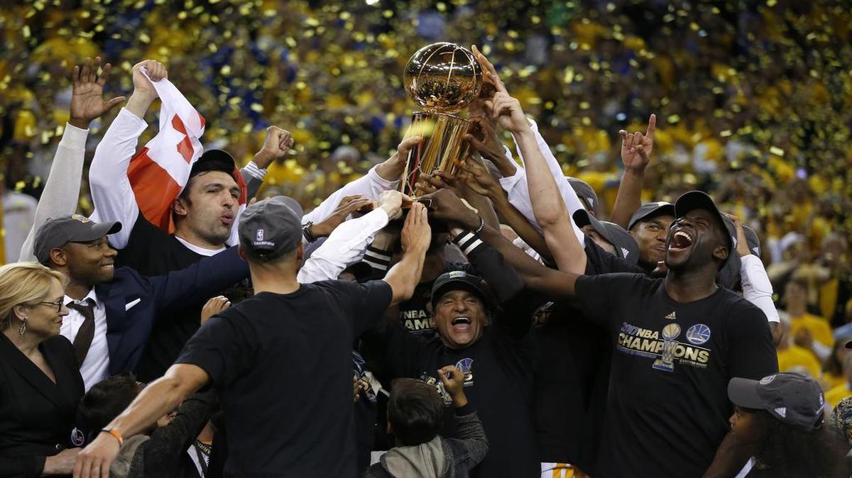 Los jugadores y el propiedario de los Warriors de Golden State, Peter Guber, levantan el trofeo de campeones de la NBA, tras derrotar en el Juego 5 de las Finales a los Cavaliers de Cleveland, el lunes en Oracle Arena de Oakland.