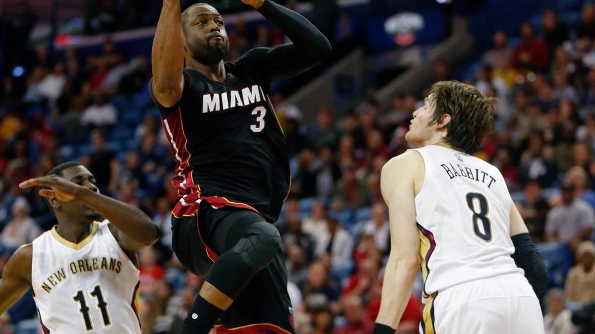 El escolta del Heat Dwyane Wade (#3) entra al aro en Jrue Holiday (#11) y Luke Babbitt, de los Pelicans, el martes en New Orleans.