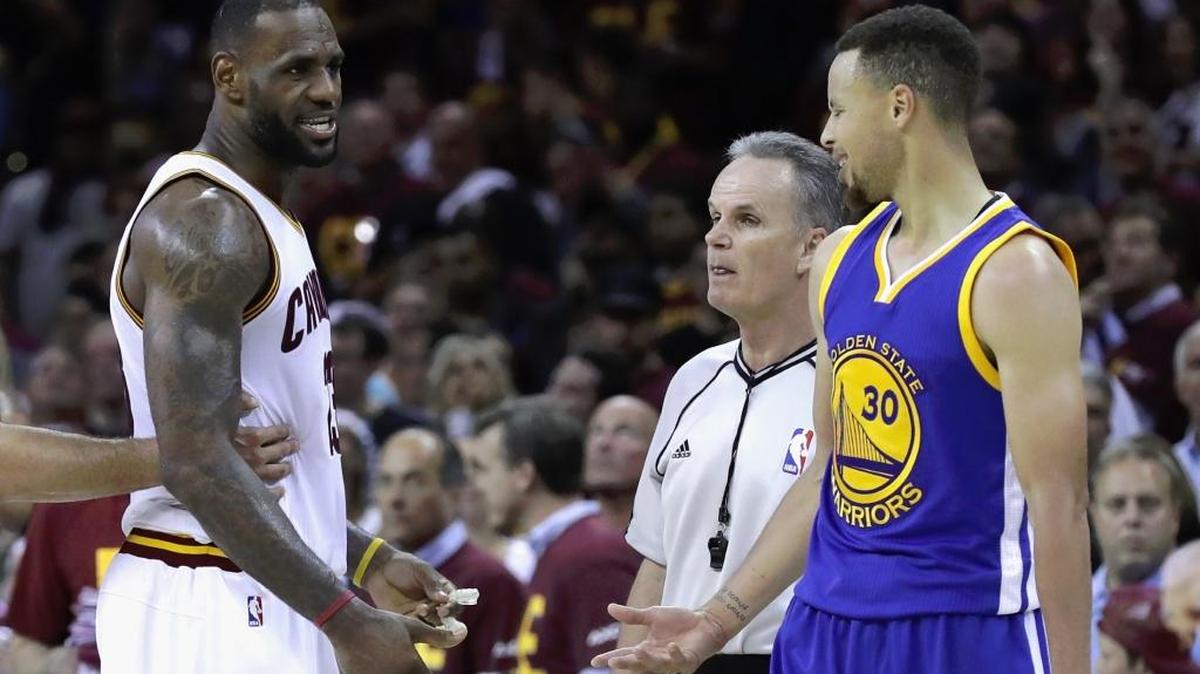 El astro de los Cavaliers LeBron James (izq.) intercambia palabras con la estrella de los Warriors Stephen Curry #30 en los minutos finales del Juego 4 el viernes en Cleveland.
