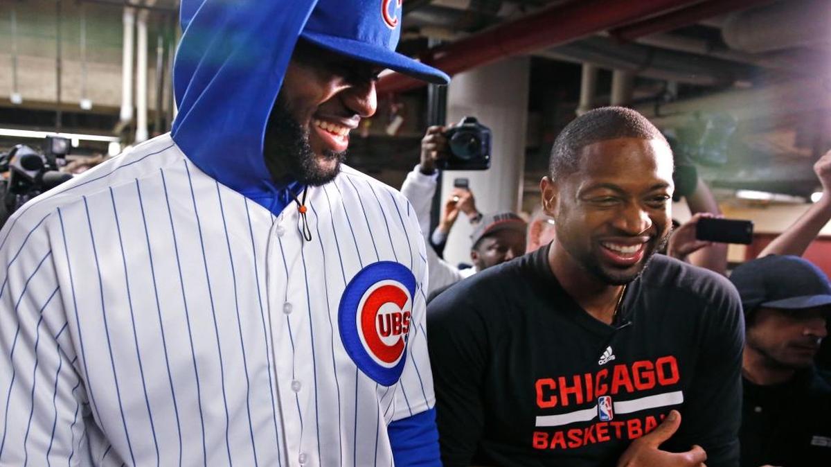 Dwyane Wade (der.), de los Bulls, y LeBron James, de los Cavaliers, con el uniforme de los Cachorros de Chicago, sonríen el viernes 2 de diciembre del 2016, en Chicago, antes de enfrentarse los dos equipos de la NBA. LeBron vistió así por el pago de una apuesta entre los excompañeros del Heat de Miami.