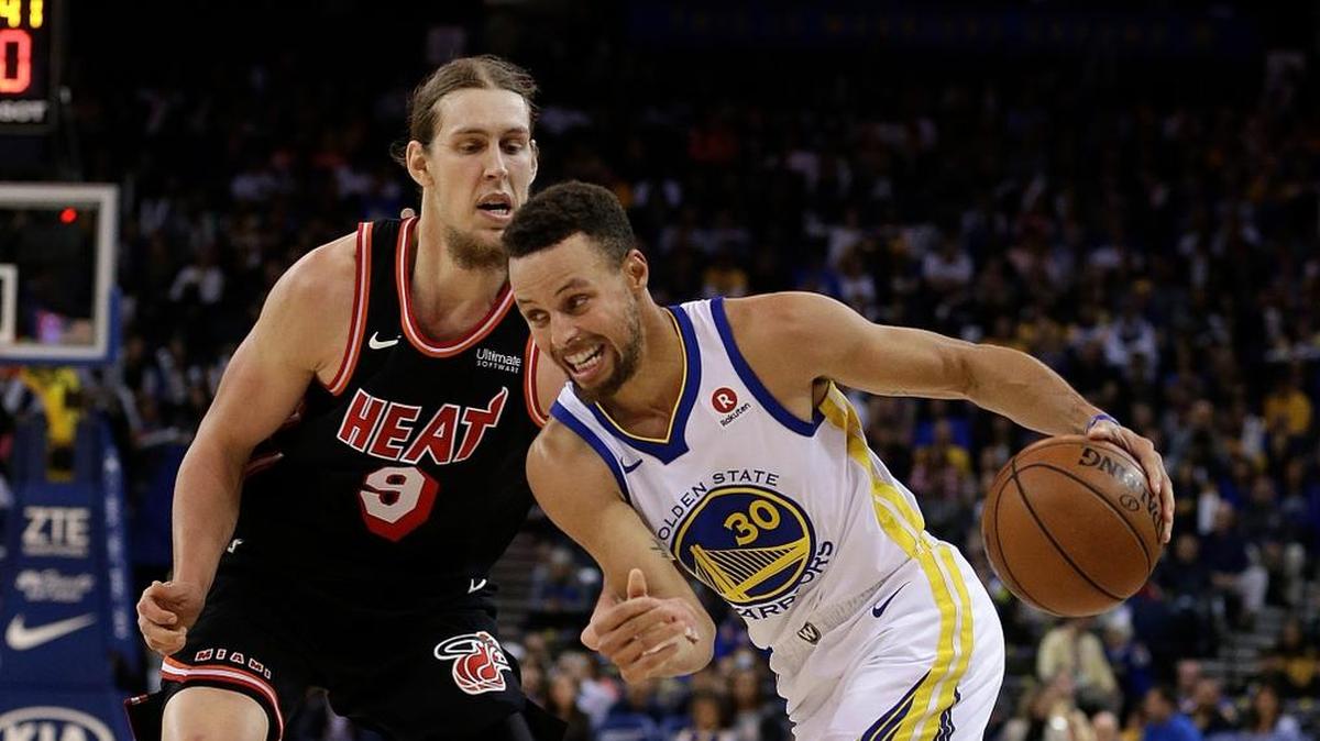 Stephen Curry, de los Warriors (der.) trata de penetrar al aro ante la marca del jugador del Heat Kelly Olynyk, en la noche del lunes en Oakland.