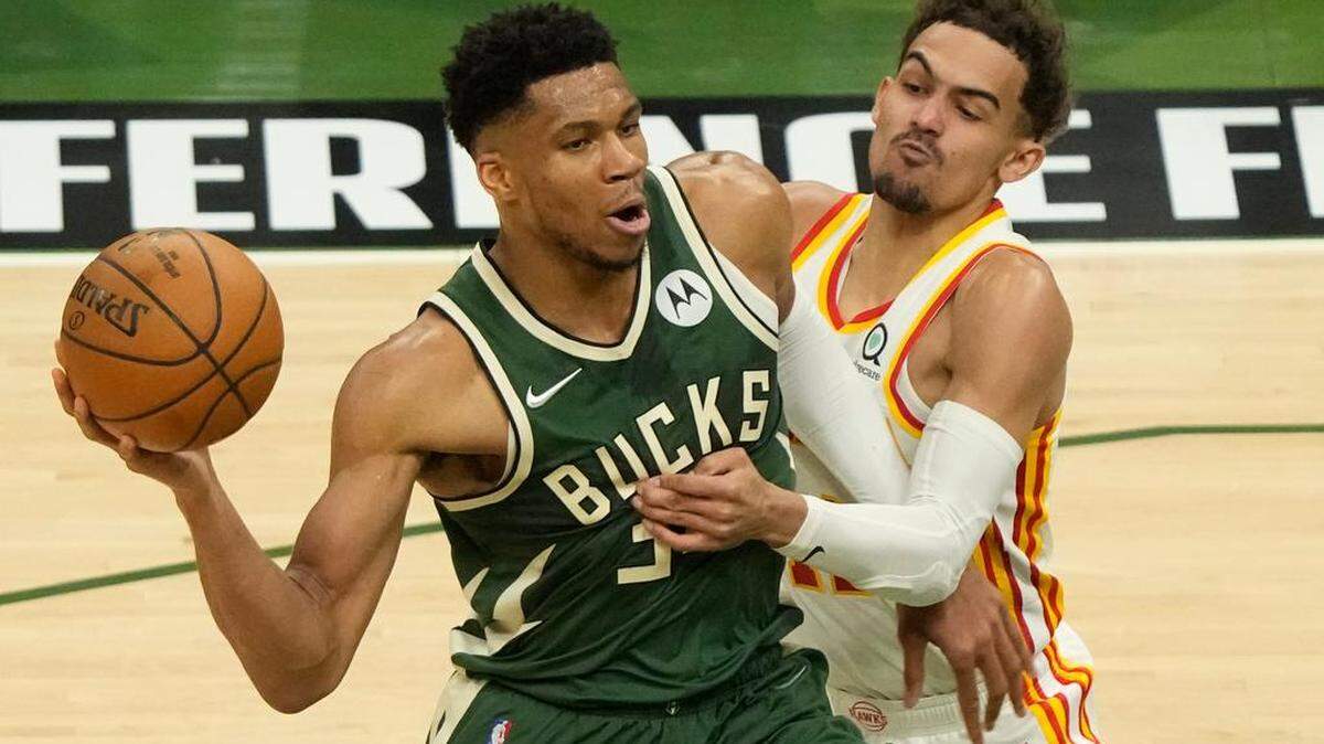 Giannis Antetokounmpo, de los Bucks (izq.) trata de pasar el balón ante la marca de Trae Young, de los Hawks, el 23 de junio en Milwaukee. 