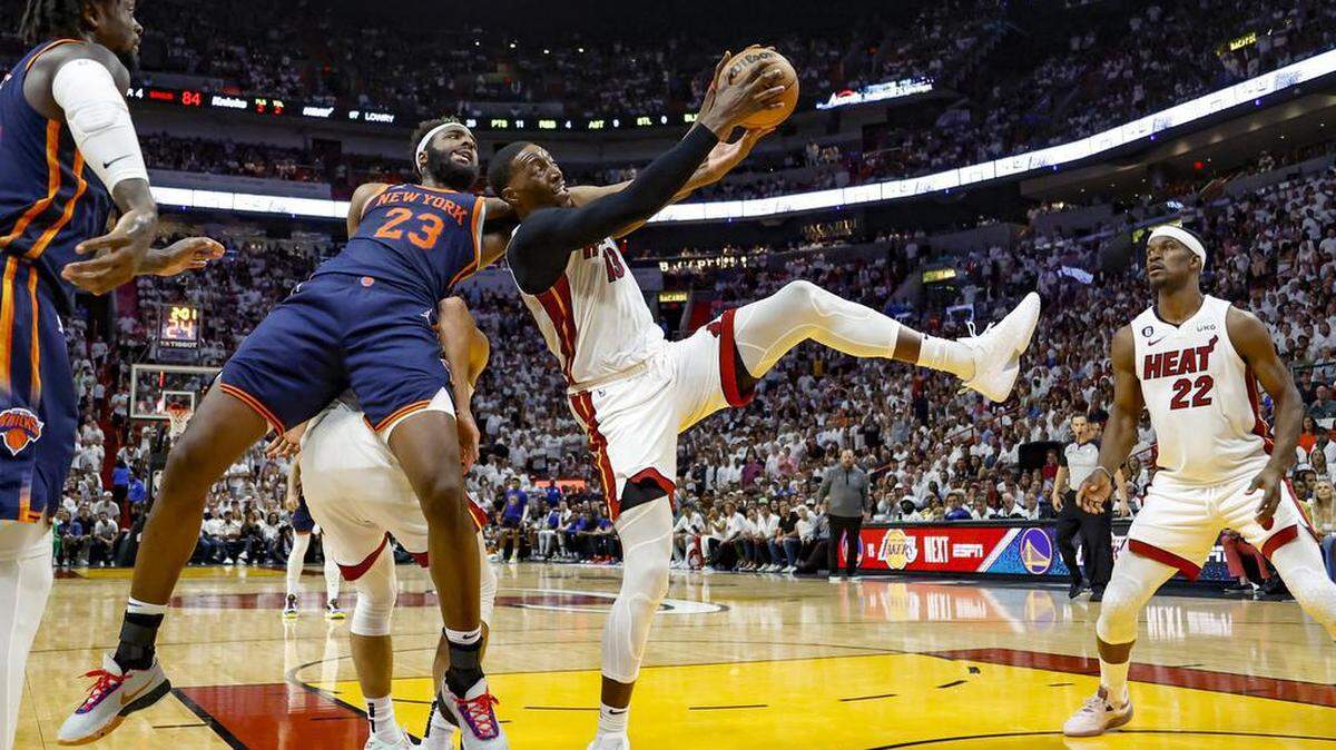El centro del Heat, Bam Adebayo (der.), toma un rebote por delante del jugador de los Knicks, Mitchell Robinson (23) ante la mirada de Jimmy Butler, en el Juego 6 de las Semifinales de la Conferencia Este de la NBA, celebrado el viernes 12 de mayo de 2023 en Miami.
