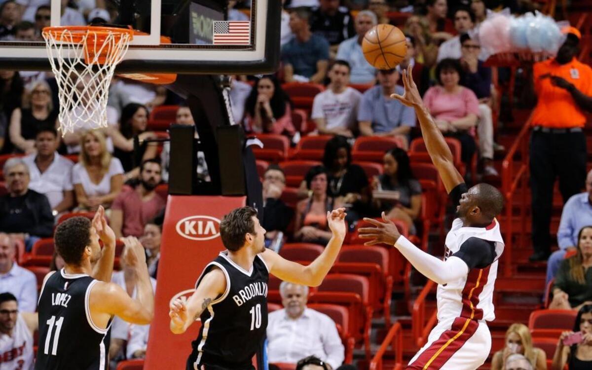 El escolta del Heat Dwyane Wade (der.) tira al aro ante la marca de los jugadores de los Nets Sergey Karasev (centro) y Brook López, el lunes 28 de marzo del 2016 en Miami.