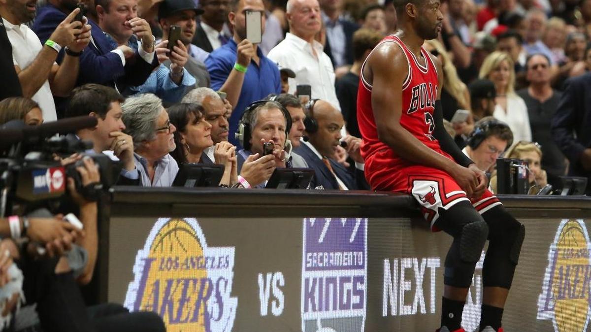 Dwyane Wade, con el uniforme de los Bulls, descansa sobre la mesa donde se encontraban el CEO del Heat, Nick Arison; el propietario, Micky Arison, y su esposa, Madeleine Arison (de izq. a der.) en el partido contra Miami, el 10 de noviembre en el American Airlines Arena.