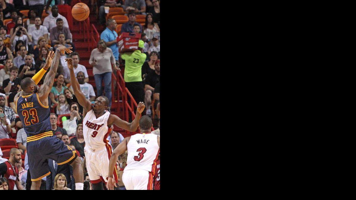 
LeBron James (izq.) tira al aro por Cleveland ante la marca de Luol Deng, del Heat, en el partido efectuado el lunes en Miami.


