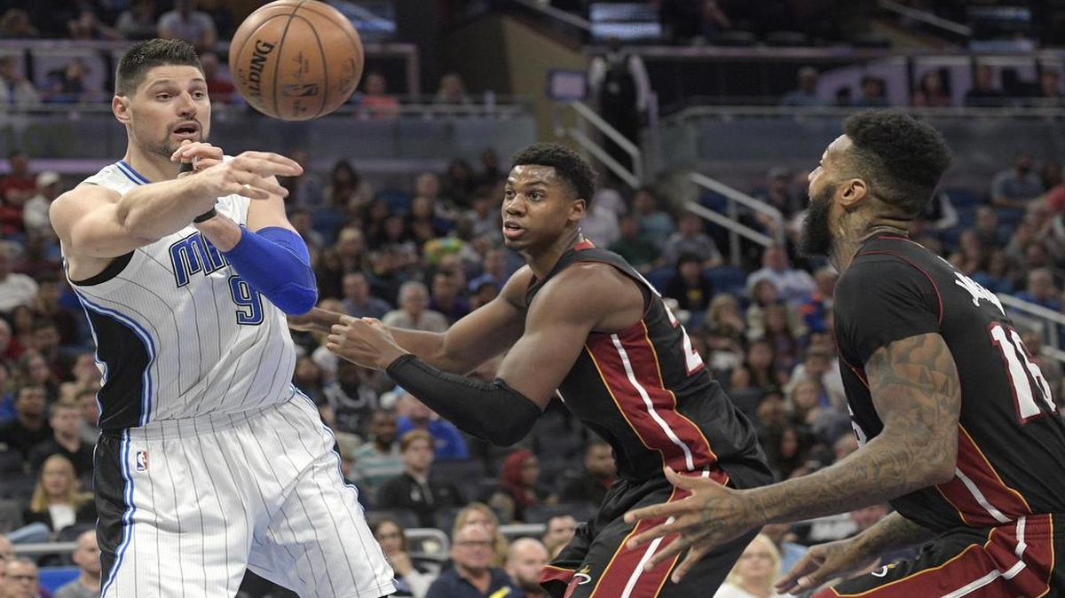 El centro del Magic Nikola Vucevic (izq.) pasa el balón ante la marca del centro del Heat Hassan Whiteside y el delantero James Johnson (der.). Vicevic y Johnson fueron los mejores de sus respectivos equipos.