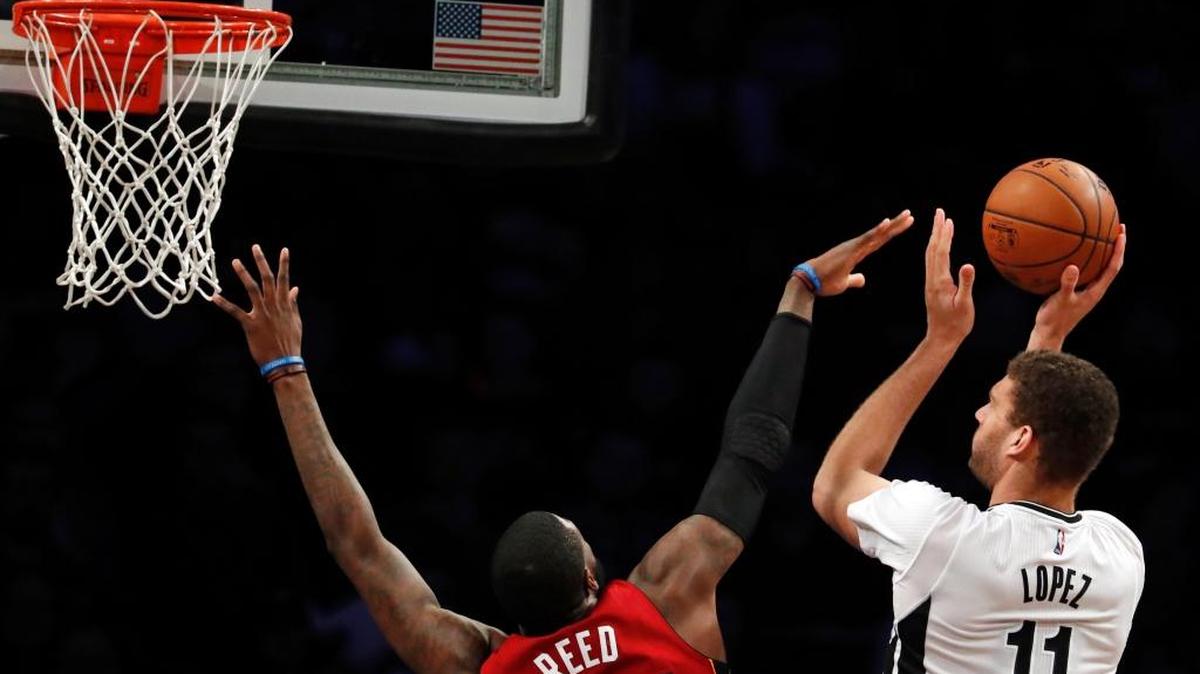 El centro de los Nets Brook Lopez (11) tira al aro ante el centro suplente del Heat Willie Reed.