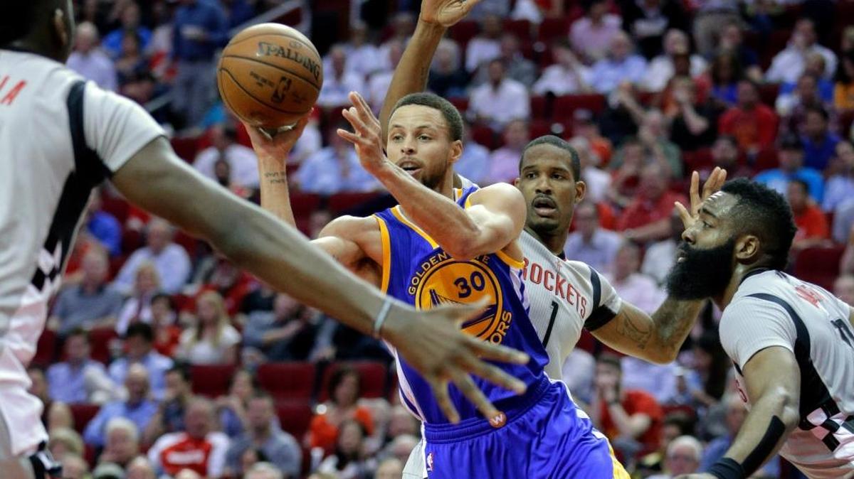Stephen Curry, de los Warriors, pasa el balón entre los jugadores de los Rockets Clint Capela (izq.), Trevor Ariza y James Harden (der.) el pasado 28 de marzo.
