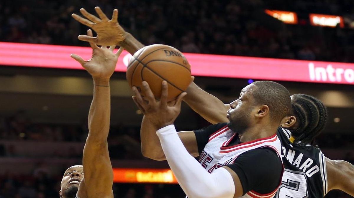 Dwyane Wade (centro) trata de entrar al aro ante la marca de David West (izq.) y Kawhi Leonard, en el partido entre el Heat y los Spurs, el martes 9 de febrero del 2016 en Miami.
