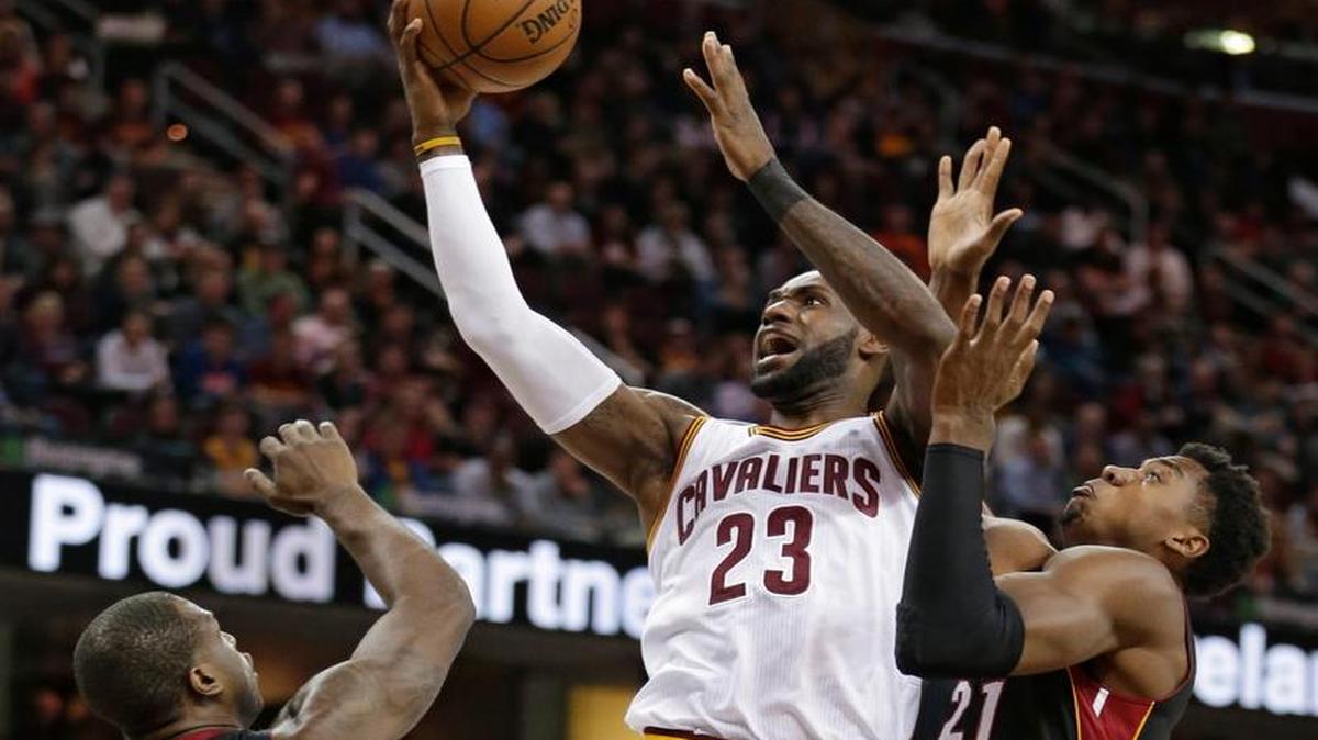 LeBron James (23), de los Cavaliers, se dispone a lanzar marcado por Dion Waiters (11) y Hassan Whiteside (21), en el triunfo del Heat el 6 de marzo pasado en Cleveland, Ohio.