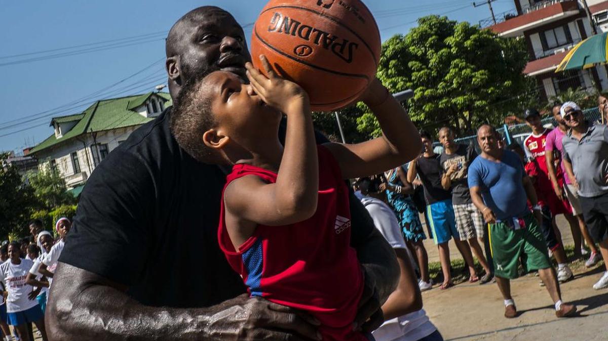 El ídolo Shaquille O'Neal ayuda a un niño a lanzar durante una clínica en La Habana, el 26 de junio del 2016.