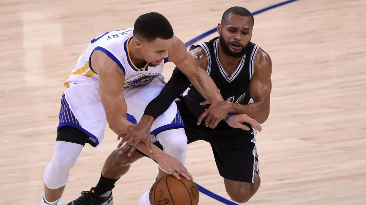 El jugador de los Warriors Stephen Curry (izq.) lucha por el balón con Patty Mills, de los Spurs, durante el partido que enfrentó a ambos equipos en el Oracle Arena en Oakland, el 25 de enero del 2016. 
