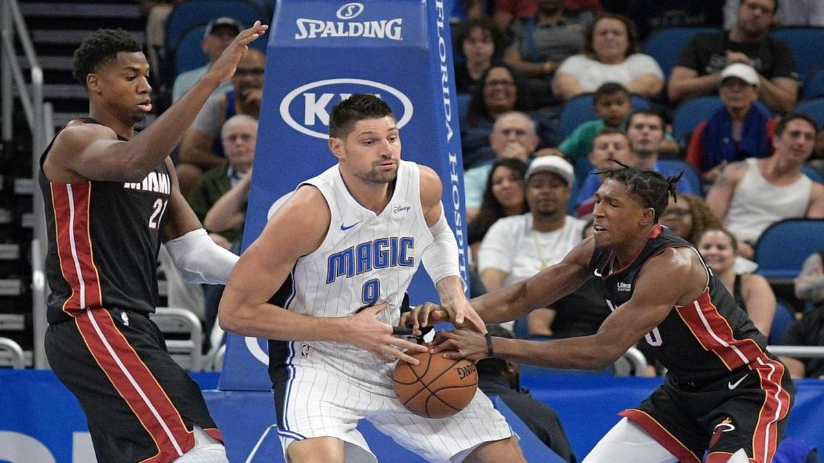 Hassan Whiteside (21) y Josh Richardson (0), del Heat, trataran de arrebatarle el balón Nikola Vucevic, del Magic, el sábado en Orlando.