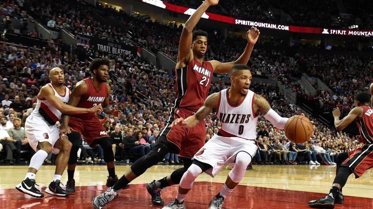 El armador de los Trail Blazers Damian Lillard (0) trata de evadir la marca del centro del Heat Hassan Whiteside (21), mientras que CJ McCollum (izq.) le cierra el paso a Justise Winslow, el sábado en Portland.