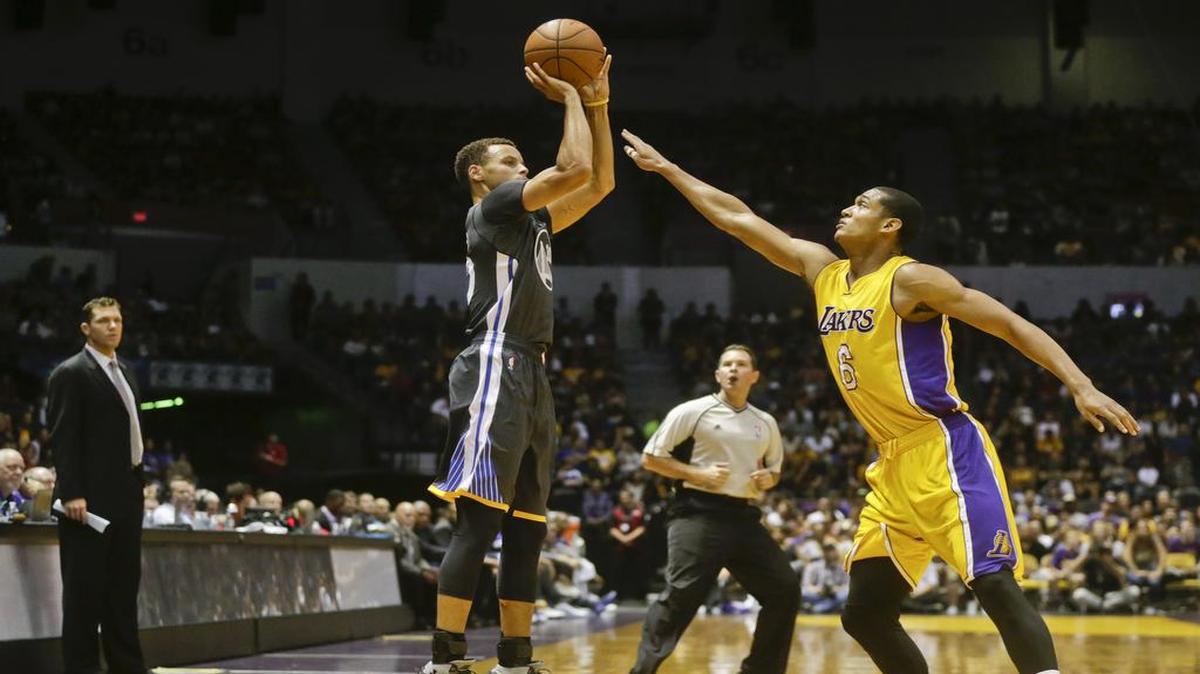 El jugador de los Warriors Stephen Curry (izq.) tira al aro ante la marca de Jordan Clarkson, de los Lakers, en un partido de pretemporada el 17 de octubre del 2015.