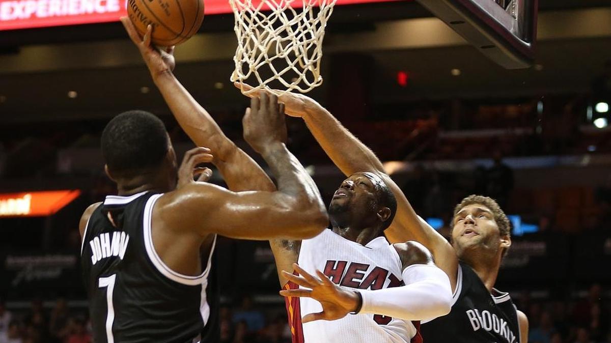 Dwyane Wade, del Heat, lucha contra Joe John y Brook Lopez, de los Nets, el lunes en Miami. Luego de un buen comienzo, el quintento de la Ciudad del Sol se desinfló.