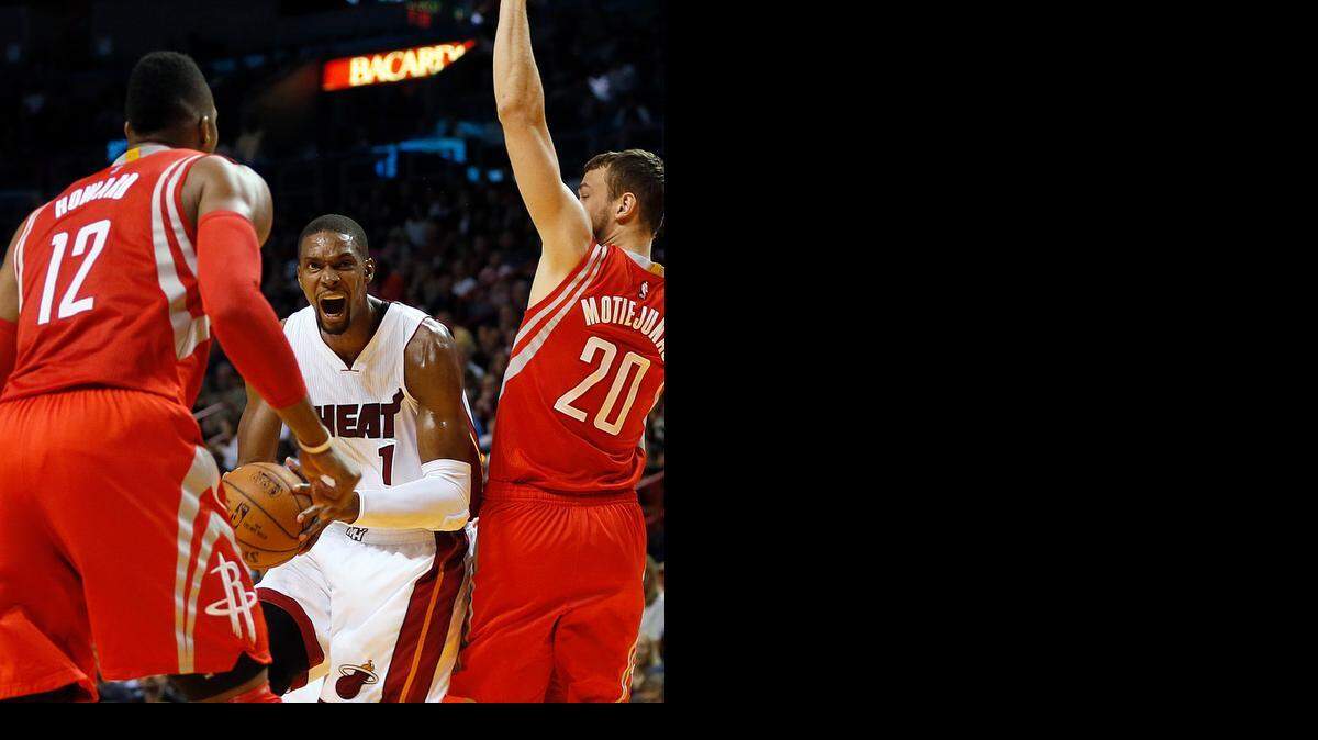 
El centro del Heat Chris Bosh (#1) trata de tirar al aro entre Dwight Howard (#12) y Donatas Motiejunas (#20), de los Rockets, el 4 de noviembre.


