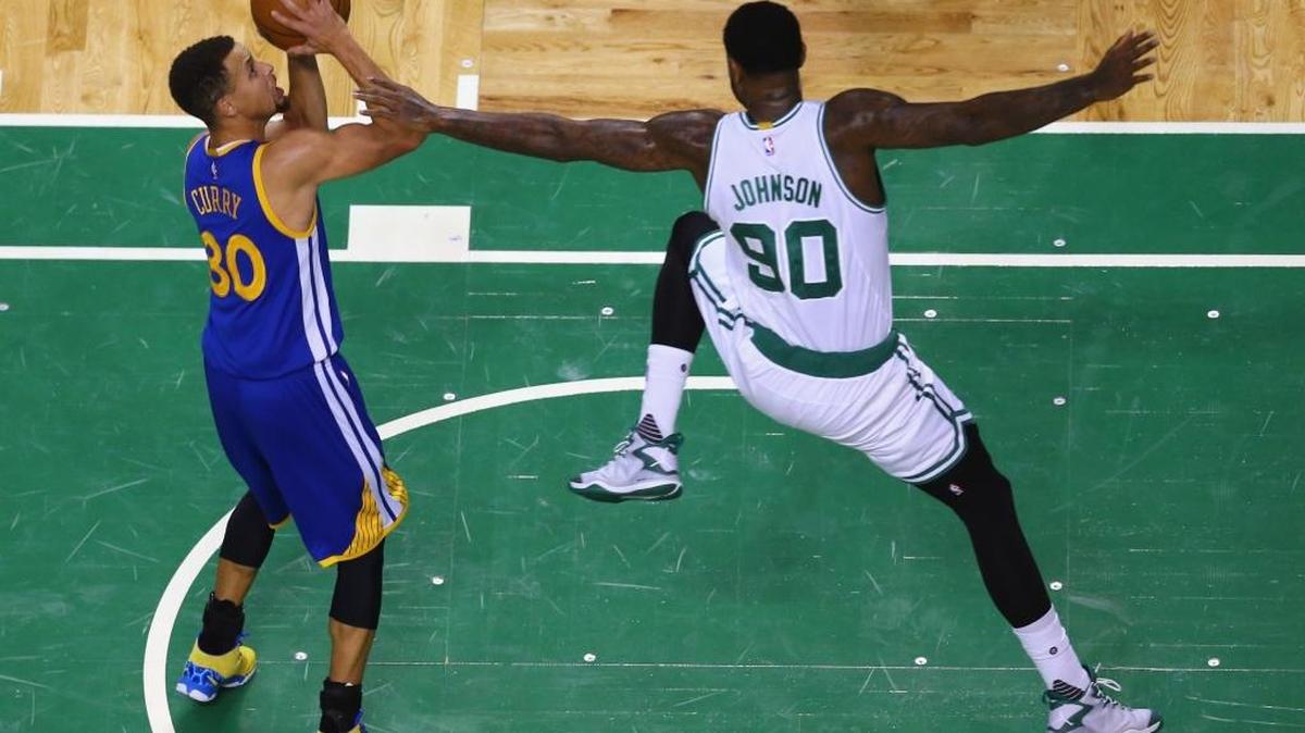 Amir Johnson (90), de los Celtics, defiende un disparo de Stephen Curry (30), de los Warriors de Golden State, en el TD Garden, el 11 de diciembre del 2015 en Boston, Massachusetts.