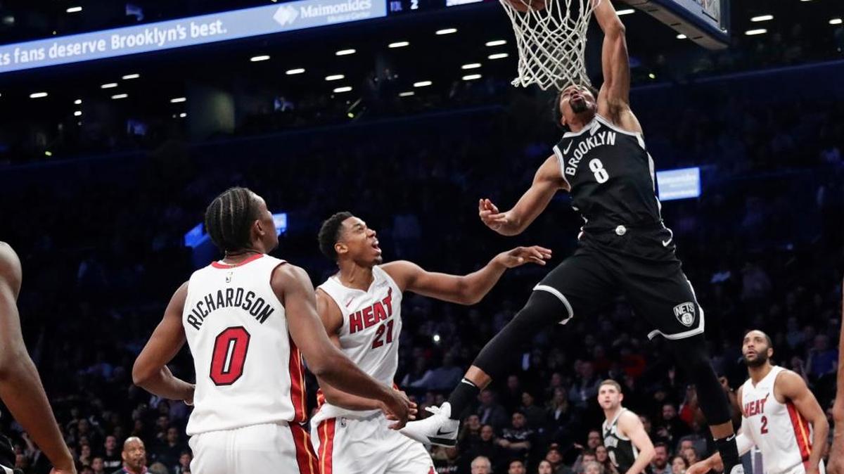 Spencer Dinwiddie (8), de los Nets, clava el balón ante los jugadores del Heat Hassan Whiteside (21) y Josh Richardson (0), el viernes en New York.